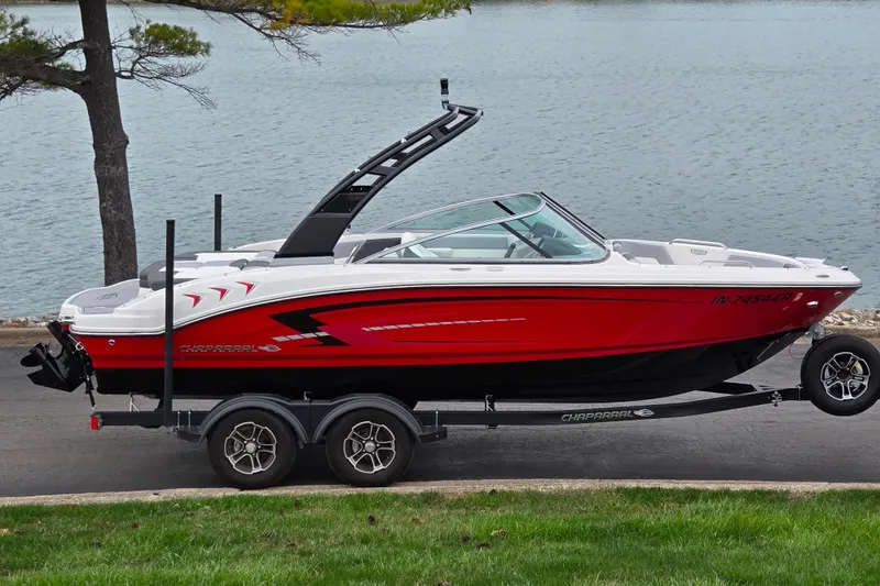 The Image of 2024 Chaparral 21 SSi boat on trailer by a lake, featuring sleek red design. - 0