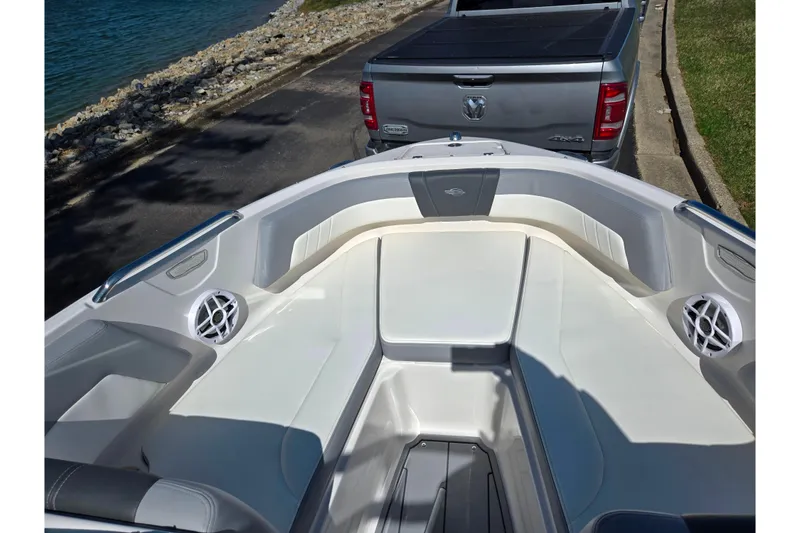 Slide: The Image of 2024 Chaparral 21 SSi boat interior with seating, parked near a silver truck by the water. - 10