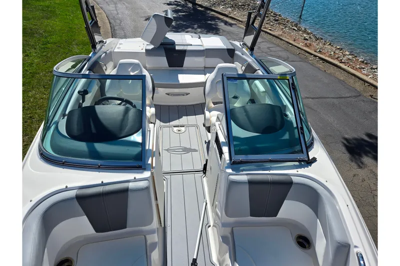 Slide: The Image of 2024 Chaparral 21 SSi boat interior with open windshield, docked by a lake. - 13