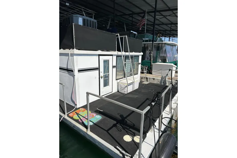 Slide: The Image of 1974 Lazy Days 14x56 houseboat docked, featuring a white exterior and black accents. - 12