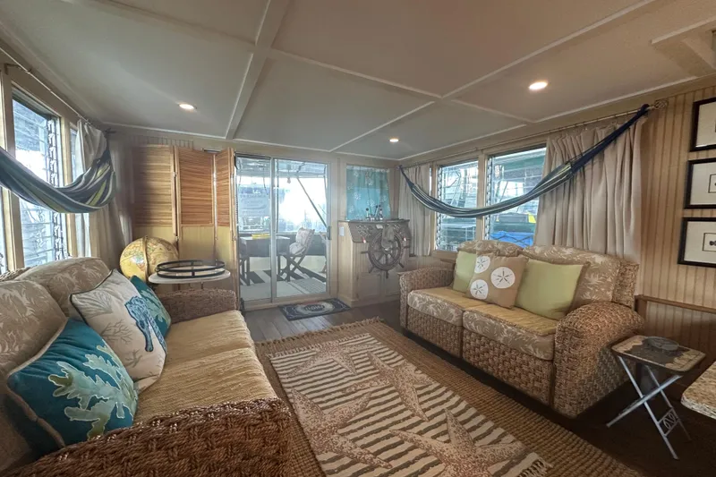 Slide: The Image of Cozy 1974 Lazy Days houseboat interior with wicker furniture, nautical decor, and large windows. - 3