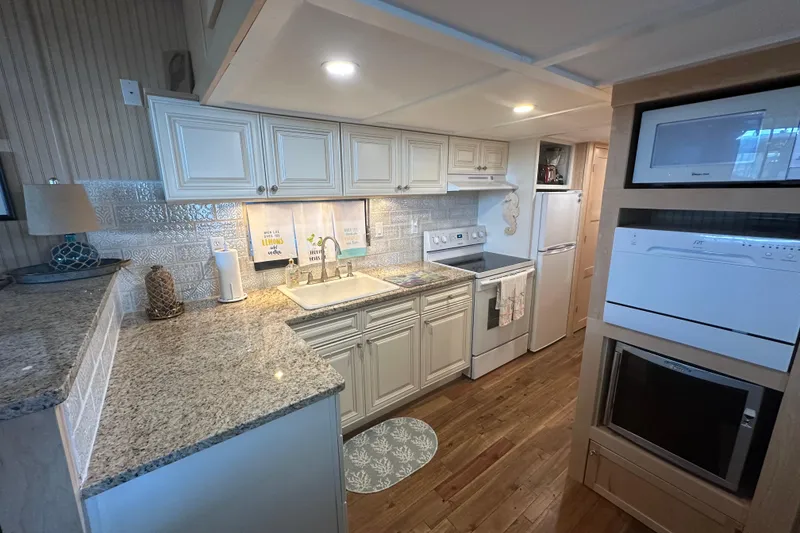 Slide: The Image of 1974 Lazy Days 14x56 kitchen with granite countertops, white cabinets, and modern appliances. - 4