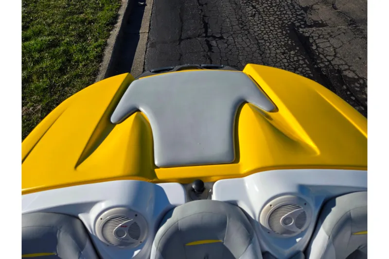 Slide: The Image of 2008 Sea-Doo 150 Speedster boat, yellow and gray interior, parked on cracked pavement. - 22