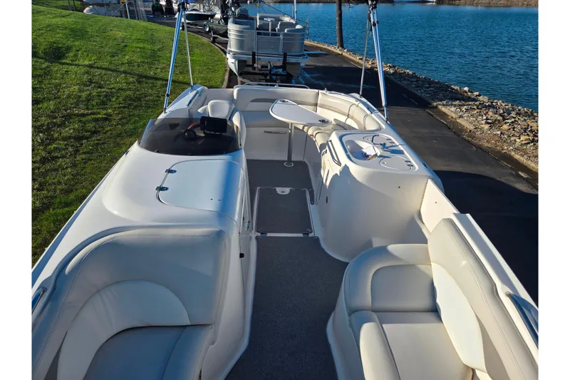 Slide: The Image of 2005 Chaparral Sunesta 232 boat interior with seating, docked by a lake. - 21