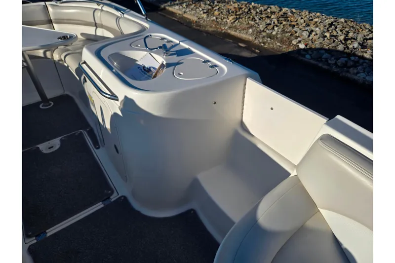 Slide: The Image of 2005 Chaparral Sunesta 232 boat interior with seating and sink, near rocky shoreline. - 22