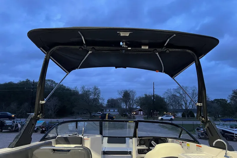 Slide: The Image of 2022 Bayliner DX 2250 boat interior with canopy at dusk, showcasing dashboard and seating. - 10
