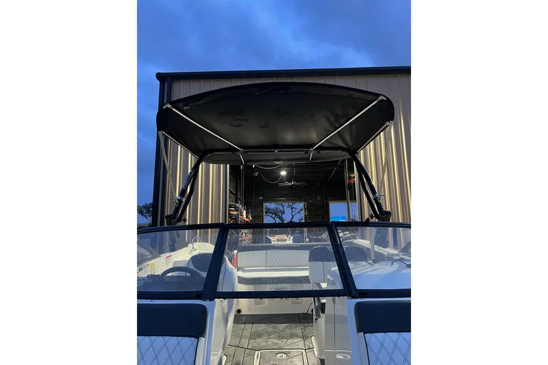Slide: The Image of 2022 Bayliner DX 2250 boat with canopy, docked at sunset. - 11