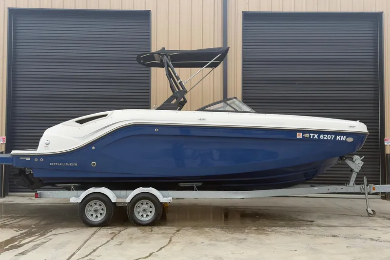 Slide: The Image of 2022 Bayliner DX 2250 boat on trailer, blue hull, parked outside. - 12