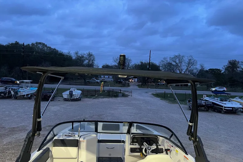 Slide: The Image of 2022 Bayliner DX 2250 boat parked at dusk with a view of the cockpit. - 9