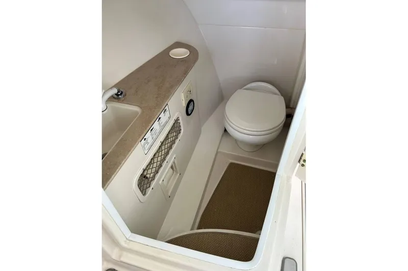 Slide: The Image of 2016 Sailfish 275 DC boat interior bathroom with toilet and sink. - 13