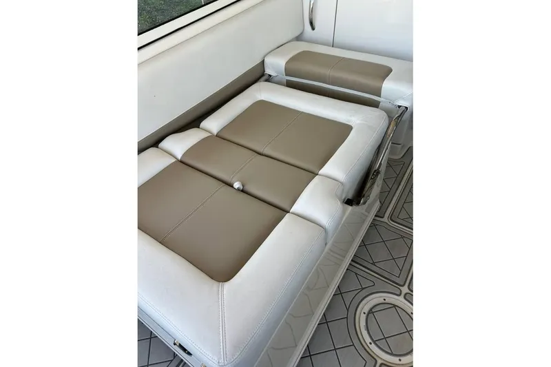 Slide: The Image of 2016 Sailfish 275 DC boat interior with beige and white cushioned seating. - 2