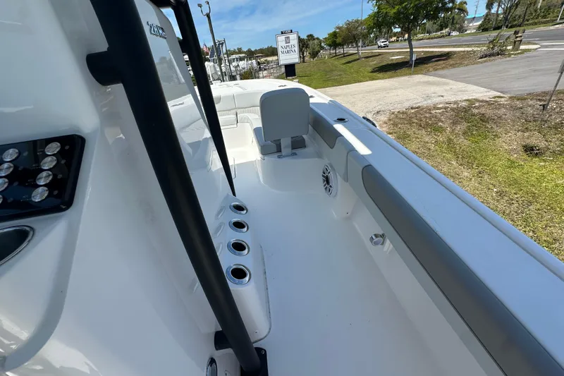 Slide: The Image of 2026 Caymas 26 HB boat interior with rod holders and seating, parked outdoors. - 11