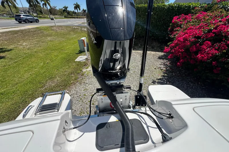 Slide: The Image of 2026 Caymas 26 HB boat with Mercury engine, parked near vibrant flowers and greenery. - 12