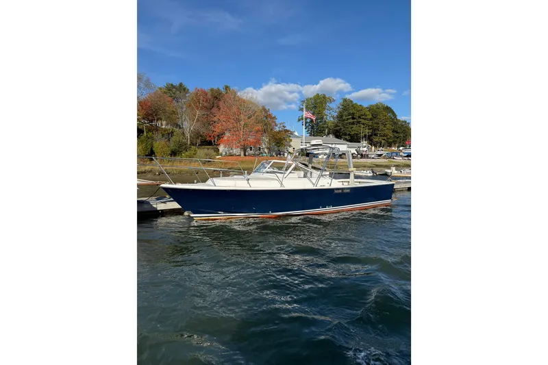The Image of 1988 Blackwatch 30 boat docked on a sunny day with autumn trees in the background. - 1