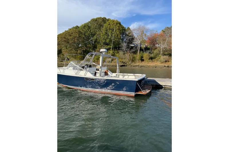 Slide: The Image of 1988 Blackwatch 30 boat docked by a scenic shoreline with trees. - 3