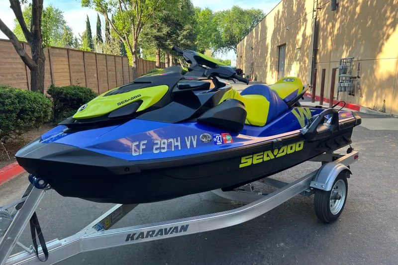 Slide: The Image of 2021 Sea-Doo Wake 170 on trailer, vibrant blue and yellow design, parked outdoors. - 3