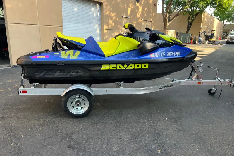Slide: The Image of 2021 Sea-Doo Wake 170 on trailer, vibrant yellow and blue design, parked outdoors. - 4