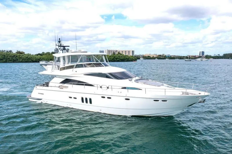 Slide: The Image of Luxury 2020 Fairline 68 yacht cruising on a scenic waterway under a partly cloudy sky. - 1