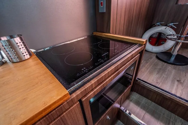 Slide: The Image of Modern kitchen area on 2020 Fairline 68 yacht with induction cooktop and wooden cabinetry. - 29