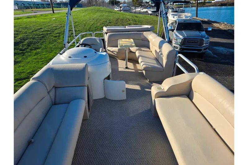 Slide: The Image of 2005 Lowe Trinidad 220 pontoon boat with beige seating, parked near a waterfront. - 11