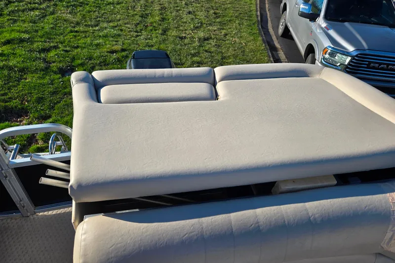 Slide: The Image of 2005 Lowe Trinidad 220 boat with beige seating, parked near a grassy area and a truck. - 15