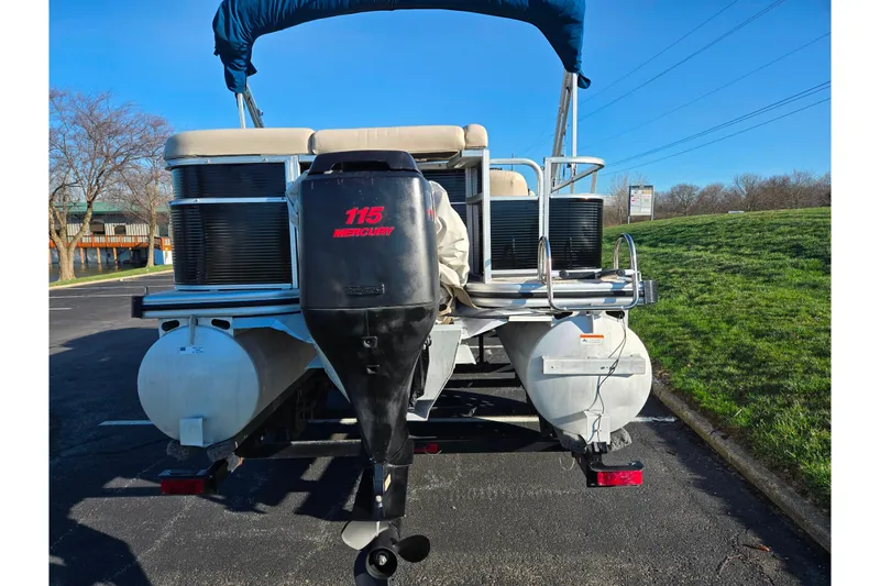 Slide: The Image of 2005 Lowe Trinidad 220 pontoon boat with Mercury 115 outboard motor, parked on pavement. - 2
