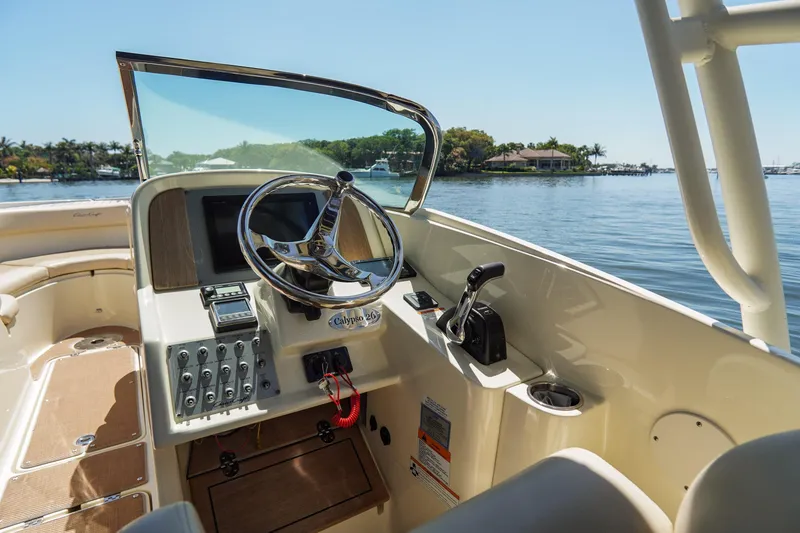 Slide: The Image of 2017 Chris-Craft Calypso 26 boat helm with steering wheel and controls on a sunny day. - 17