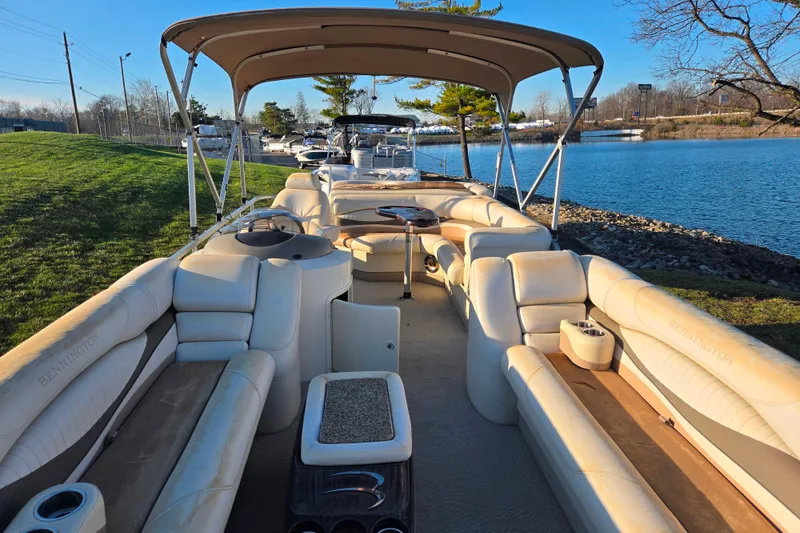 Slide: The Image of 2008 Bennington 2275RL pontoon boat with beige seating, docked by a serene lake. - 11