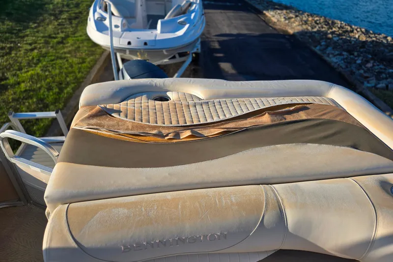 Slide: The Image of 2008 Bennington 2275RL boat with worn upholstery near a dock and water. - 17