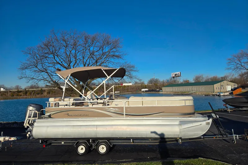 Slide: The Image of 2008 Bennington 2275RL pontoon boat on trailer by a lake under clear blue sky. - 9
