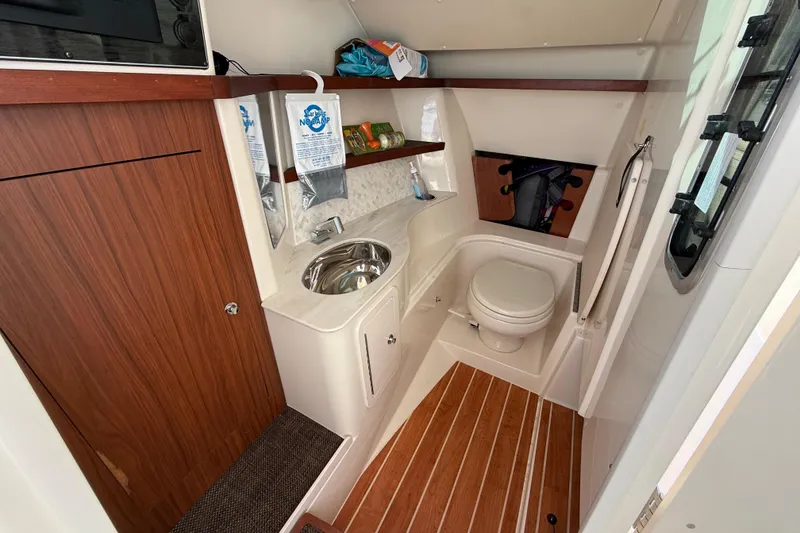 Slide: The Image of 2020 Grady-White Freedom 325 boat interior with wooden cabinetry, sink, and toilet. - 20