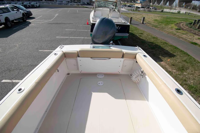 Slide: The Image of 2020 NorthCoast 235 HT boat interior with cushioned seating and spacious deck in a parking area. - 5