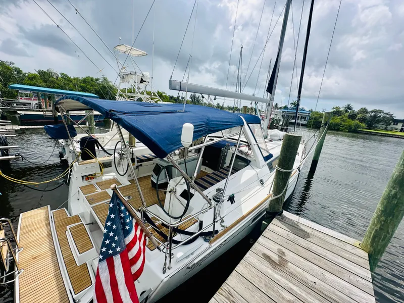 Slide: The Image of 2015 Beneteau Oceanis 45 sailboat docked, featuring blue canopy and American flag. - 20