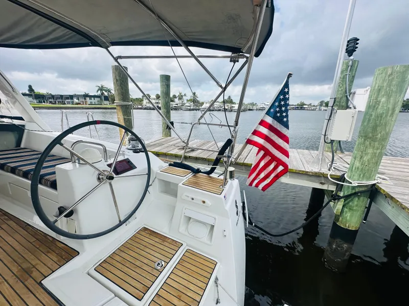 Slide: The Image of Beneteau Oceanis 45 sailboat cockpit with American flag, docked by a marina. - 24