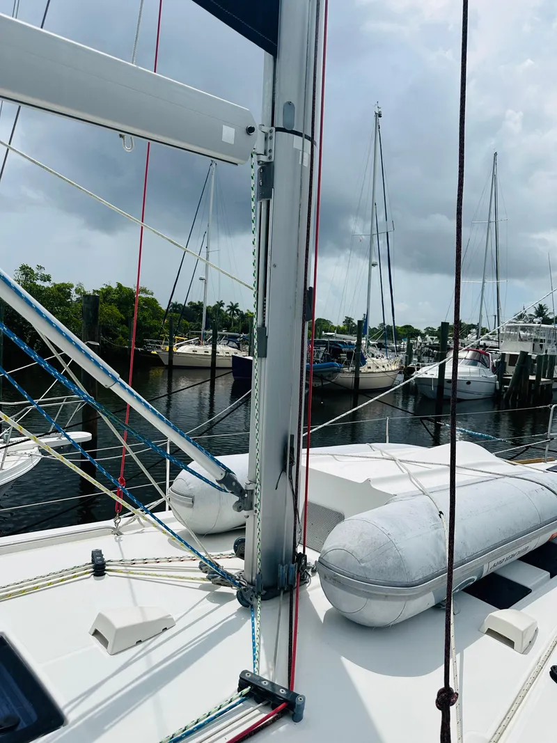 Slide: The Image of 2015 Beneteau Oceanis 45 sailboat docked, featuring mast and rigging, with cloudy sky backdrop. - 33