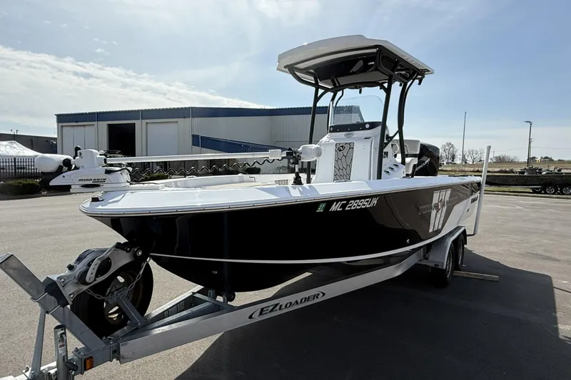 Slide: The Image of 2019 Wellcraft 221 Bay boat on trailer, parked outdoors under clear sky. - 2