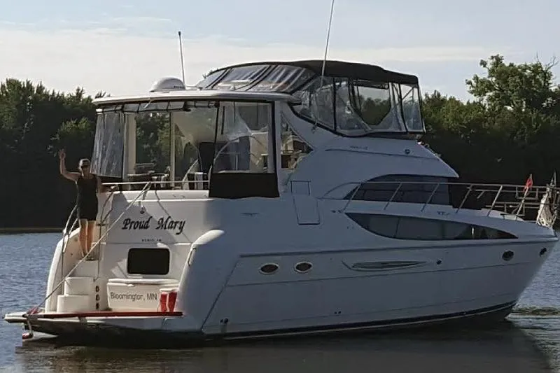The Image of 2004 Meridian 408 Motoryacht on water, person waving from deck, trees in background. - 0