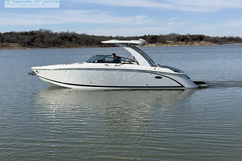 Slide: The Image of 2021 Cobalt R30 boat cruising on a calm lake with wooded shoreline. - 2