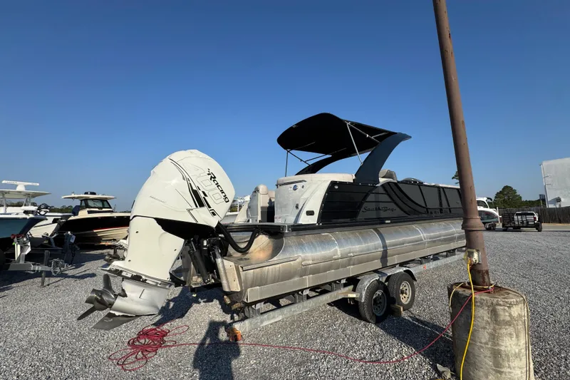 Slide: The Image of 2018 South Bay 725RS pontoon boat on trailer, parked outdoors under clear blue sky. - 11