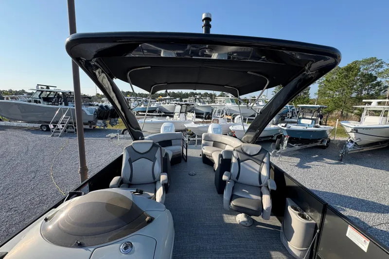 Slide: The Image of 2018 South Bay 725RS pontoon boat interior with seating and canopy, docked among other boats. - 20