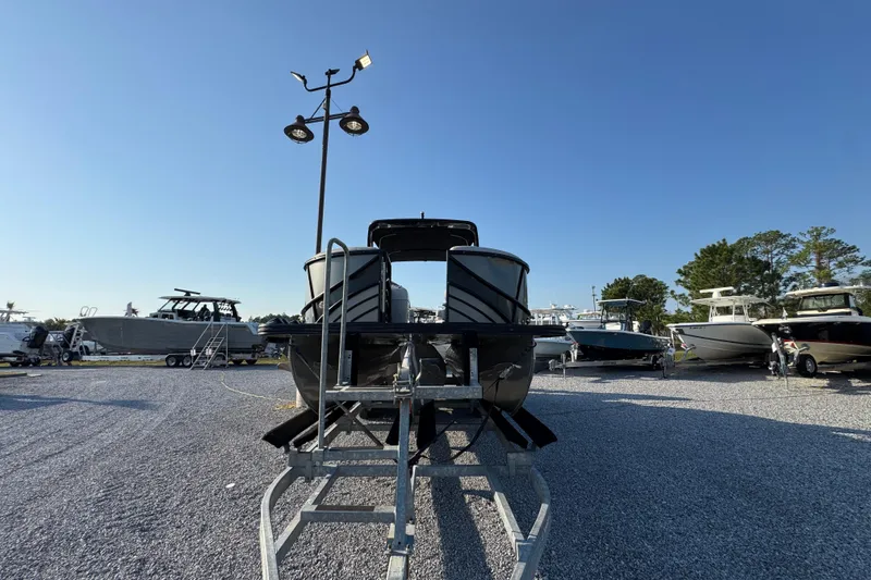 Slide: The Image of 2018 South Bay 725RS pontoon boat on trailer in a boatyard under clear blue sky. - 6