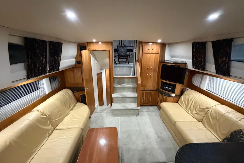 Slide: The Image of Interior of 2001 Carver 444 Cockpit Motor Yacht with beige sofas and wooden cabinetry. - 2