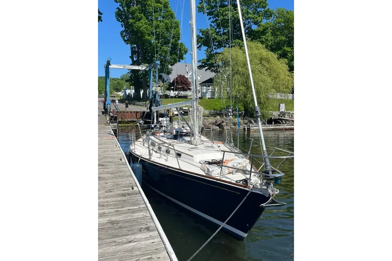 Slide: The Image of 1987 Sabre 42 sailboat docked by a wooden pier, surrounded by lush greenery. - 2