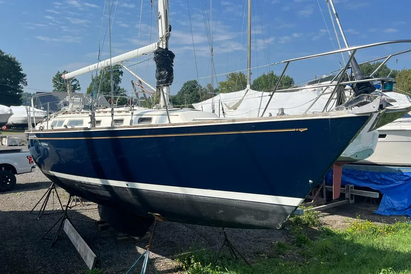 Slide: The Image of 1987 Sabre 42 sailboat on land, blue hull, white deck, clear sky background. - 22