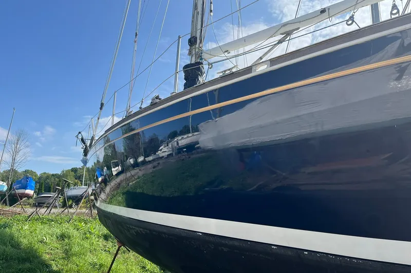 Slide: The Image of 1987 Sabre 42 sailboat on land, blue hull, clear sky background. - 23
