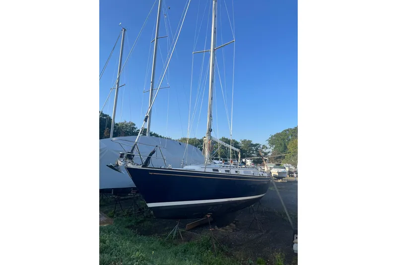 Slide: The Image of 1987 Sabre 42 sailboat on land, blue hull, clear sky background. - 24