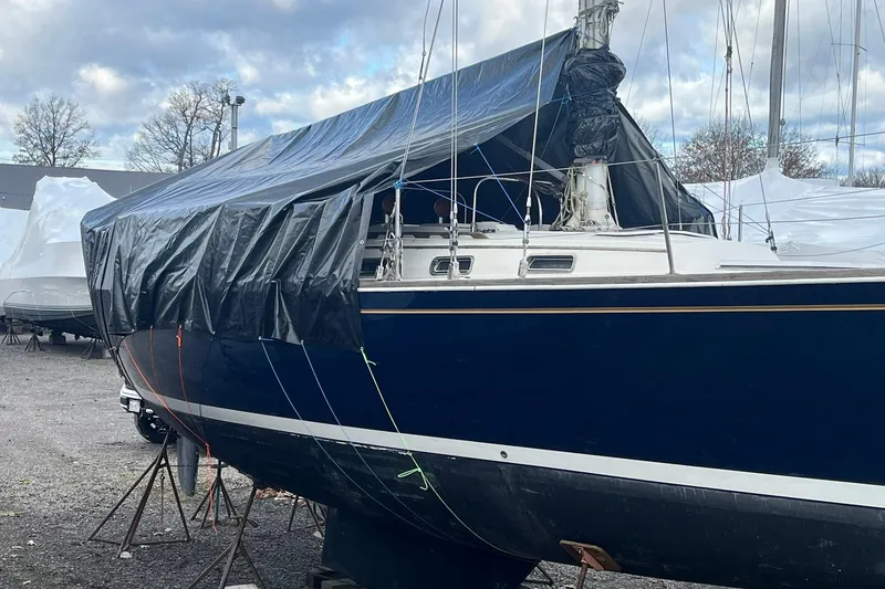 Slide: The Image of 1987 Sabre 42 sailboat covered with tarp, stored on land under cloudy sky. - 30