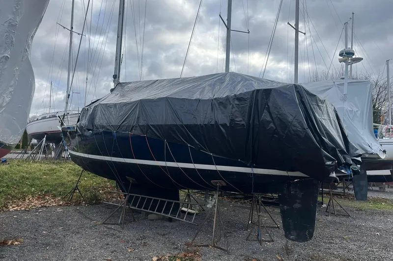 Slide: The Image of 1987 Sabre 42 sailboat covered with tarp, stored on land with overcast sky. - 31