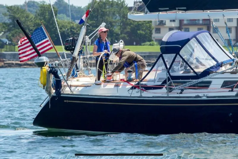 Slide: The Image of 1987 Sabre 42 sailboat with crew, American flag, sailing near shore. - 6