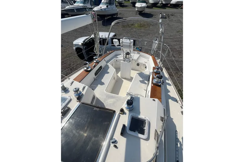 Slide: The Image of 1987 Sabre 42 sailboat cockpit with winches and wooden trim, docked on gravel. - 8